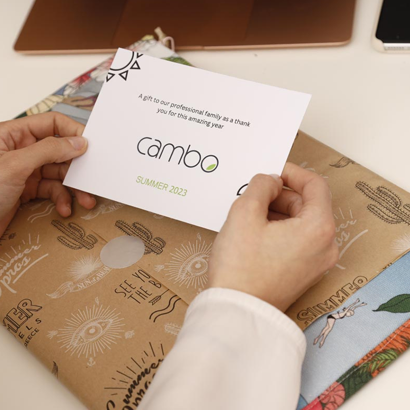 An employee’s hands holding a thank-you note while opening a corporate gift, symbolizing appreciation and recognition in the workplace.