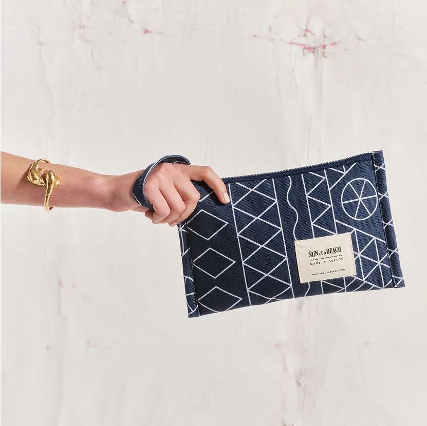 A woman’s hand holding a blue pouch with white stripes in front of a white wall designed for premium corporate gift.